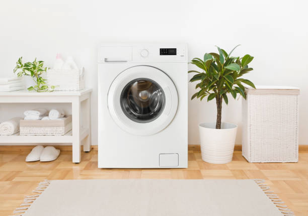 istock Modern washing machine, towels and related objects in laundry room 1298251112