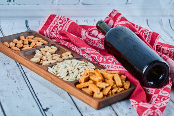 Assorted snacks and a bottle of wine on the blue table. Crackers, sunflower seed, pistachios, almonds. High quality photo