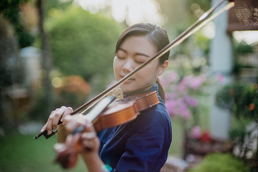 Young woman playing violin in front yard