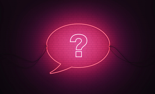 Speech bubble shaped pink neon light with question mark on black wall. Horizontal composition with copy space. Q and A  and help concept.