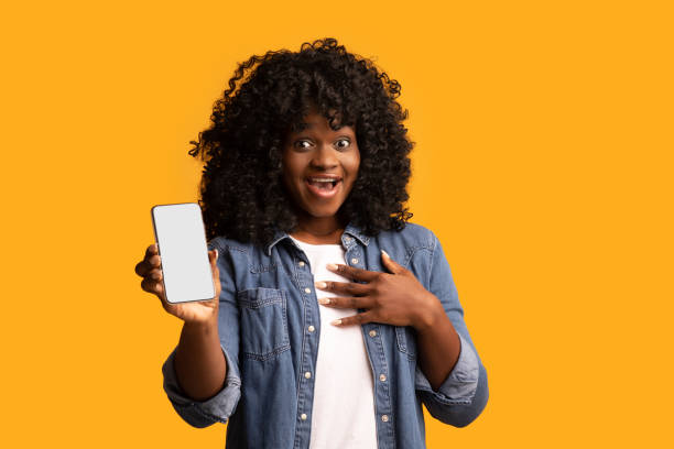 istock Amazed black lady showing smartphone with empty screen 1298252553