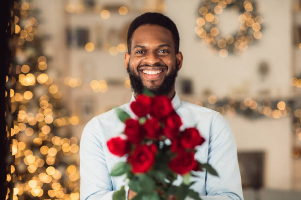 roses de fixation d’homme noir de sourire, donnant à l’appareil-photo - anniversary couple rose black photos et images de collection