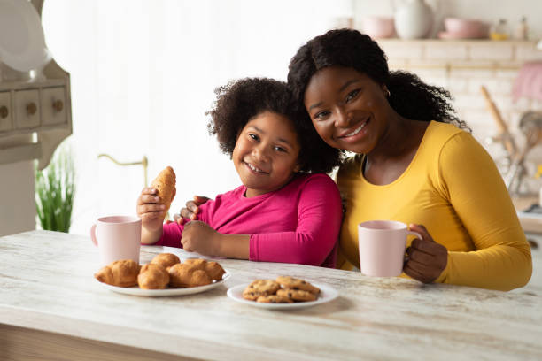 istock African mother and little daughter having a bite in kitchen together 1298253579