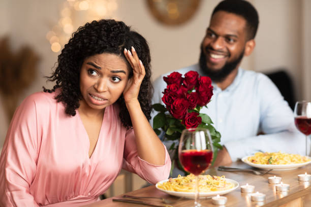 Black Woman On Unsuccessful First Date In Restaurant Bad First Impression And Blind Date Concept. Dissatisfied shocked black woman rejecting excited emotional obsessed man who giving her flowers, young couple sitting at table in cafe embarrassment stock pictures, royalty-free photos & images