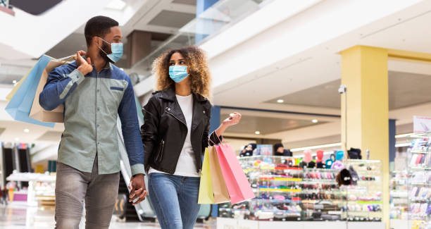 African american couple in love spending time together in mall African american loving couple in protective face masks spending time together after shopping in mall center, panorama with free space. Black man and woman walking by shopping mall during quarantine mall walker stock pictures, royalty-free photos & images