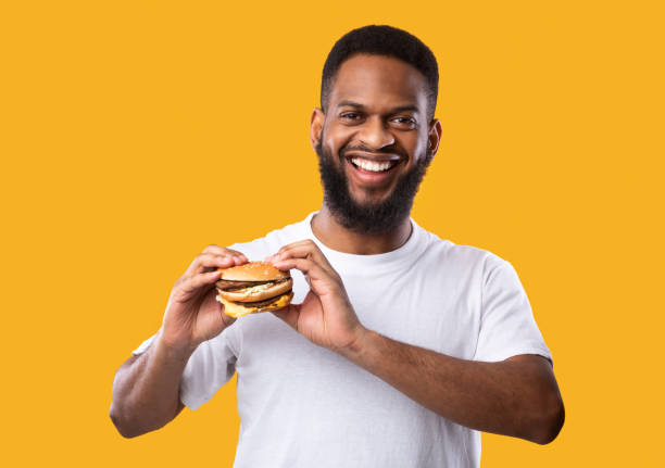 istock Black man posing holding burger smiling to camera, studio shot 1298255221