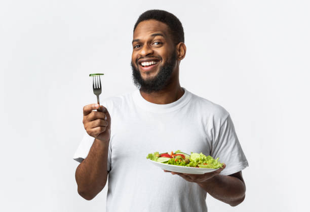 istock Smiling African American Guy Posing With Vegetable Salad, White Background 1298255459