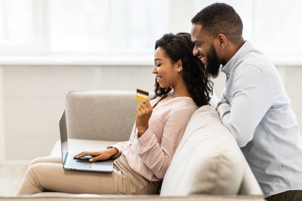 istock Black couple using computer and debit credit card at home 1298255673