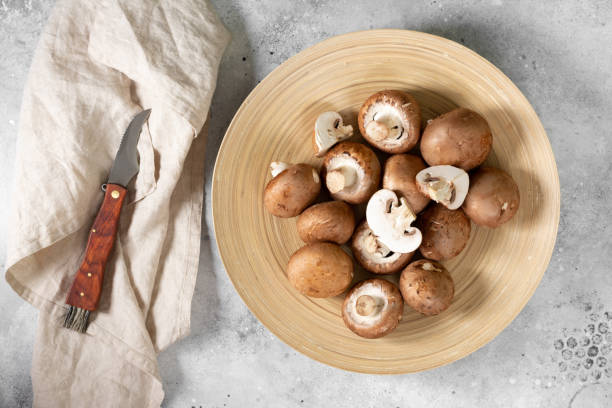 istock Mushrooms in a wooden plate on the light gray kitchen table. Champignons 1298257169