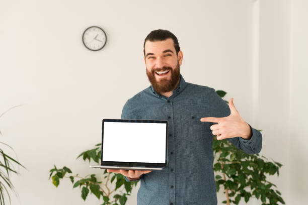 istock Cheerful office worker man pointing at empty screen on laptop with copyspace 1298257299