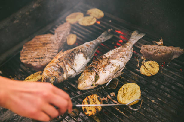 cooking fish and potatoes on grill - prepared fish seafood barbecue grilled imagens e fotografias de stock