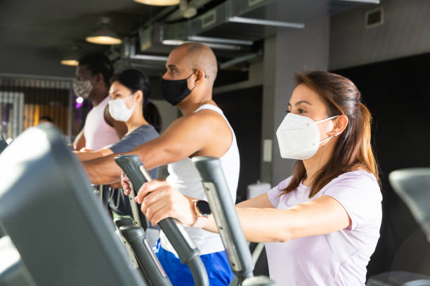 istock Active people in protective masks having running elliptical trainer class in club 1298258512
