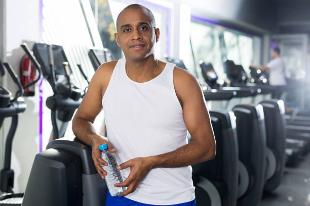 istock Man drinking water after exercises in gym 1298258571