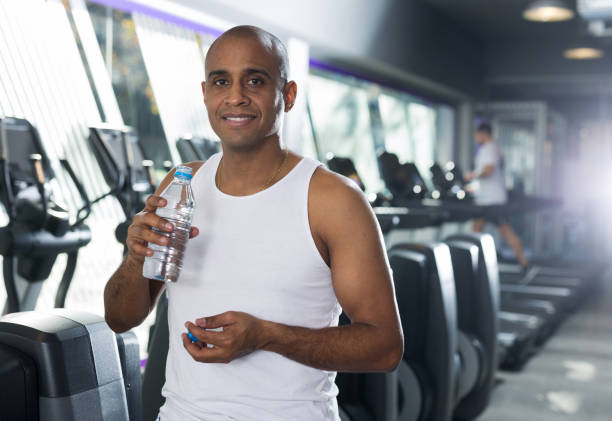 istock Man drinking water after exercises in gym 1298258574