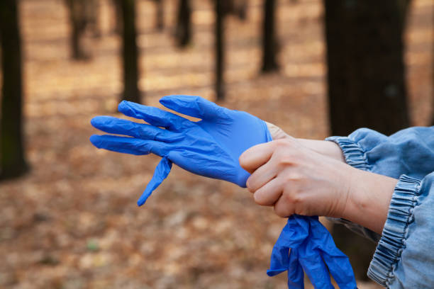 istock Hands put on rubber gloves in forest 1298260050