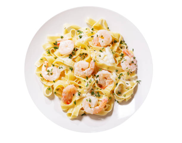 plate of pasta fettuccine with cream sauce and shrimps isolated on a white background plate of pasta fettuccine with cream sauce and shrimps isolated on a white background, top view food state preparation shrimp prepared shrimp stock pictures, royalty-free photos & images