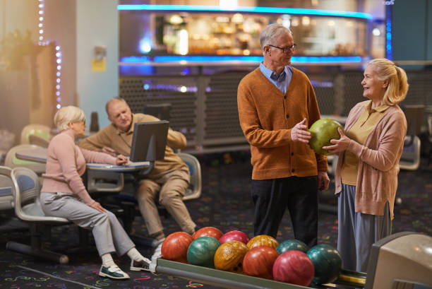 радостная старшая пара, играющая в боулинг - bowling holding bowling ball hobbies стоковые фото и изображения