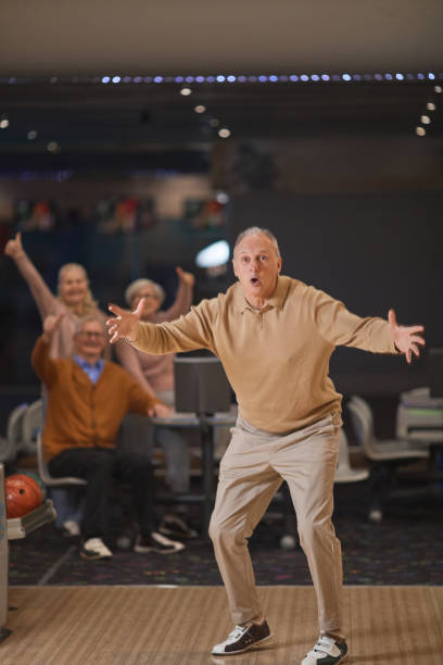 homem sênior emocional jogando boliche com amigos - bowling holding bowling ball hobbies - fotografias e filmes do acervo