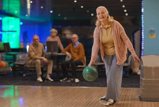 mulher sênior sorridente jogando boliche com amigos - bowling holding bowling ball hobbies - fotografias e filmes do acervo