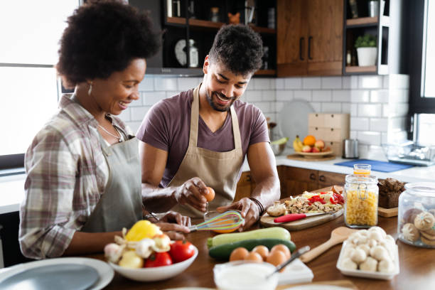 istock Beautiful young couple is talking and smiling while cooking in kitchen at home. 1298263160