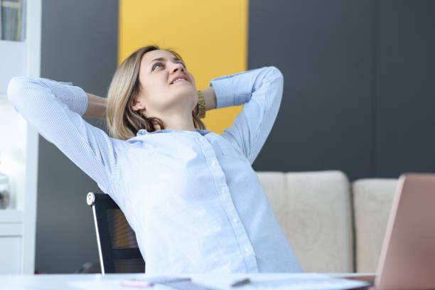 istock Happy businesswoman sits at her work table and looks at ceiling 1298264384