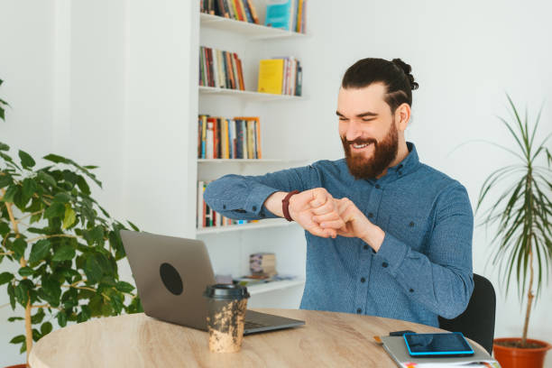 istock Cheerful bearded man in office looking at smartwatch 1298264415