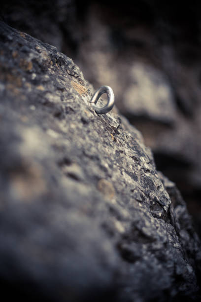 Close up shot of a metal rig drilled into stone, safety device used in rock climbing.