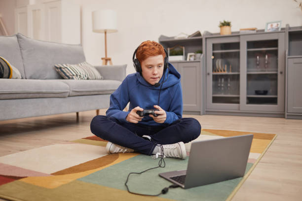 red haired boy playing video games on floor - online game imagens e fotografias de stock