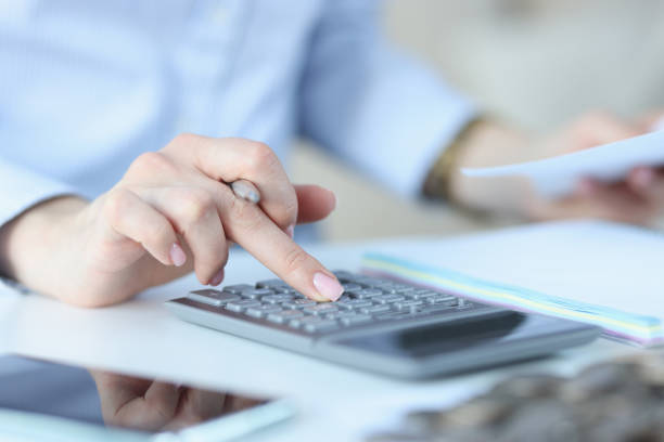 istock Female hand holds pen and presses numbers on calculator 1298264823