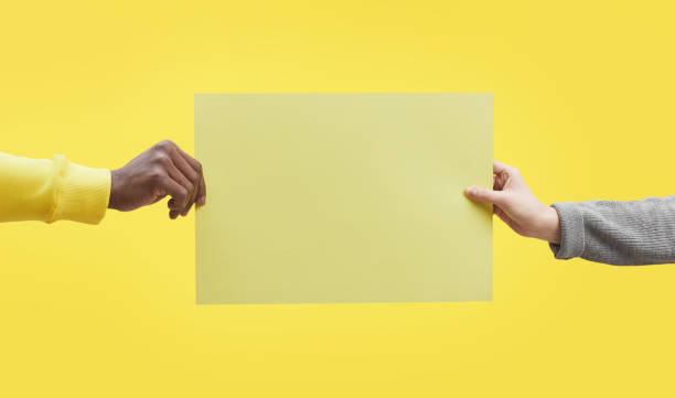 istock Two Hands Holding Sign on Yellow 1298265069