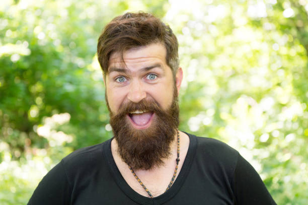 istock The beard with depth and texture. Bearded man smiling with stylish mustache and beard shape. Unshaven hipster with textured beard hair on summer outdoor. Happy caucasian guy with beard on nature 1298265981
