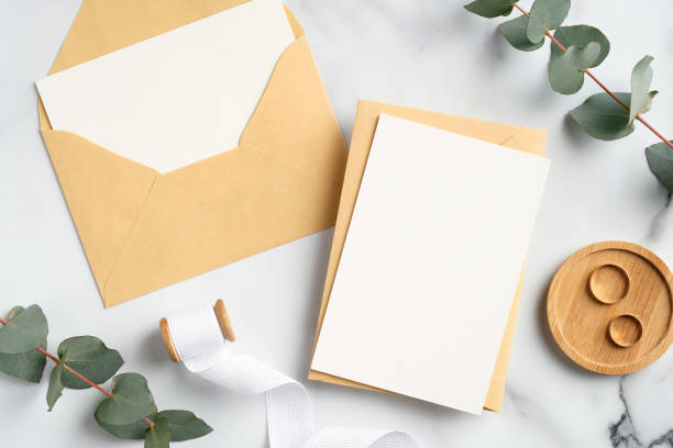 istock Wedding invitation cards, craft paper envelopes, ring, ribbon, eucalyptus branches on marble background. Bridal flat lay composition, top view. Rustic style. 1298269166