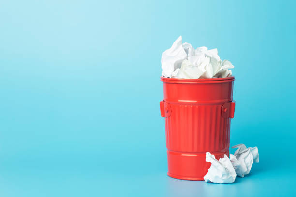 istock Paper trash and waste in a trash bin on a blue background. Waste and paper sorting and recycling concept 1298269613