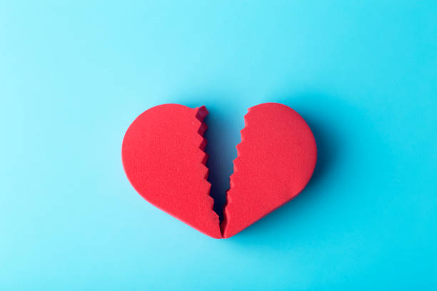 istock Broken heart on a colored background. Unhappy love, betrayal, quarrel, breakup concept. 1298269614
