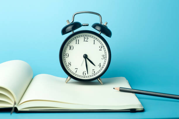 istock Notepad for sticky notes on desktop with alarm clock. Office desktop, management and timing concept. 1298269616
