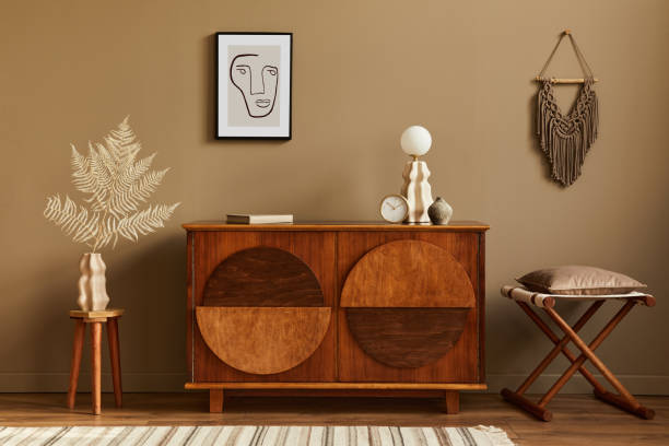 istock Stylish interior with design wooden commode, stool, dried flowers in vase, unique decoration, carpet, mock up poster frame and elegant personal accessories. Modern living room in classic house. 1298269832