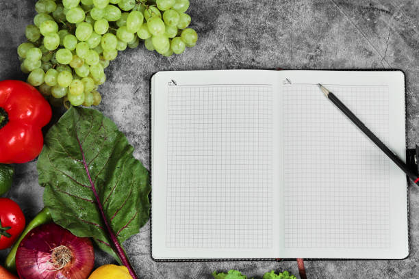 istock Grapes, peppers, greens, lemon, tomato and empty notebook on marble background 1298271433