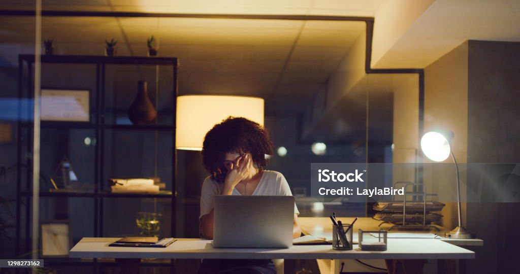 A burdened mind is an unproductive one Shot of a young businesswoman looking stressed while using a laptop during a late night at work Mental Health Stock Photo
