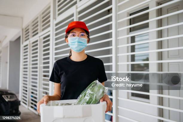 An Asian Chinese Delivery Person Holding A Box Of Fresh Vegetables Stock Photo - Download Image Now