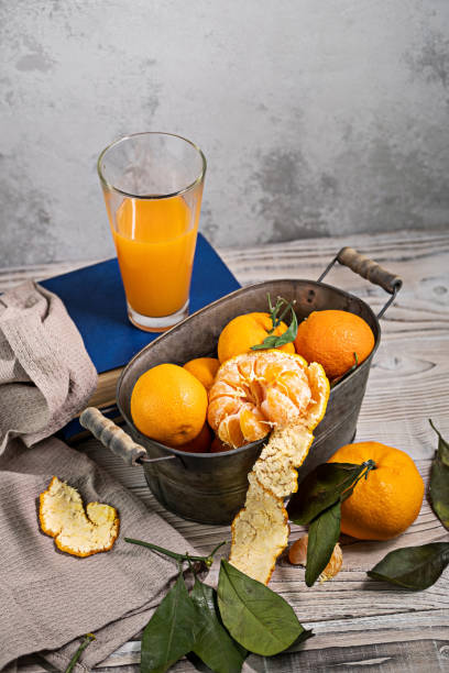 istock Several tangerines with leaves in a container lie on a white table against a light background. Rustic style copyspace. 1298274873