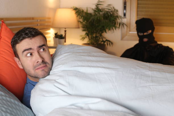 man in bed surprised by an intruder - burglary thief fear burglar imagens e fotografias de stock