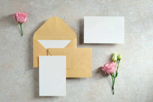 istock Blank paper card and envelopes with rose flowers on stone table. Top view, flat lay. Wedding stationery set. 1298280746