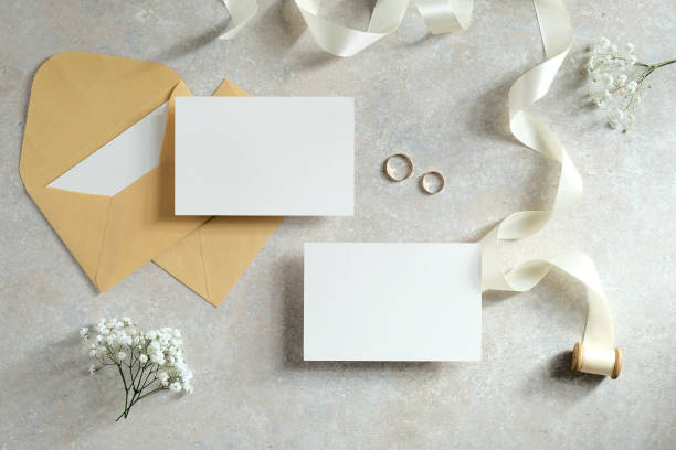 istock Wedding flat lay composition with blank paper card, envelopes, ribbon, flowers on stone table. 1298280748