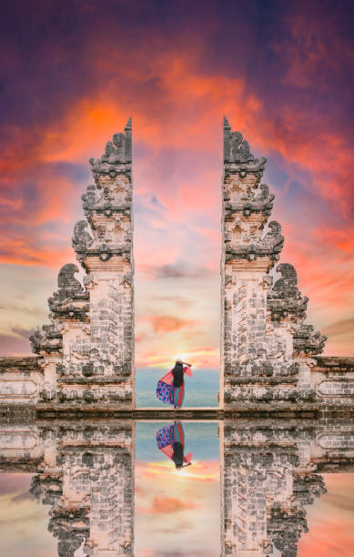 A girl is posing in front of the Gate of Heaven with its reflection in the water during a stunning sunset. stock photo