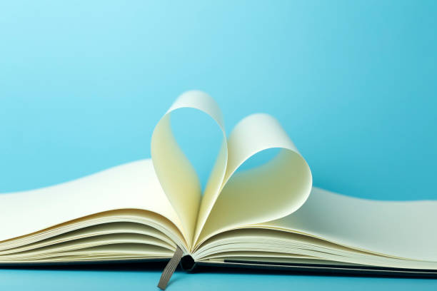istock Heart made from white pages of notepad on a blue desktop background. 1298282089