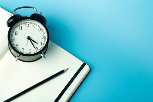 istock Notepad for sticky notes on desktop with alarm clock. Office desktop, management and timing concept. 1298282103