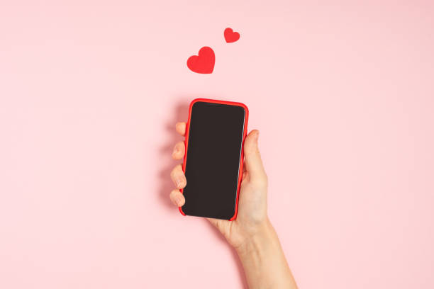istock Woman's hands holding mobile phone with blank screen with heart shape 1298282429