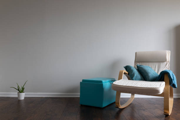 A room with hardwood floor, celery color painted wall and white fabric chair with plywood underarms with space for copy text on the wall