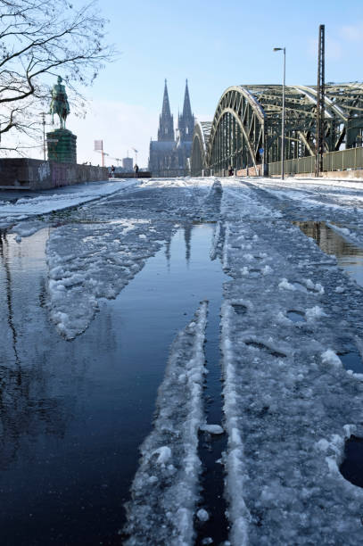 Melting snow on a paved path in Cologne, Germany, with the famous cathedral in the background