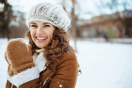 Happy woman at snowcapped meadow near forest in winter time.